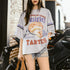 Person wearing a graphic t-shirt with text and images, standing in an urban setting.